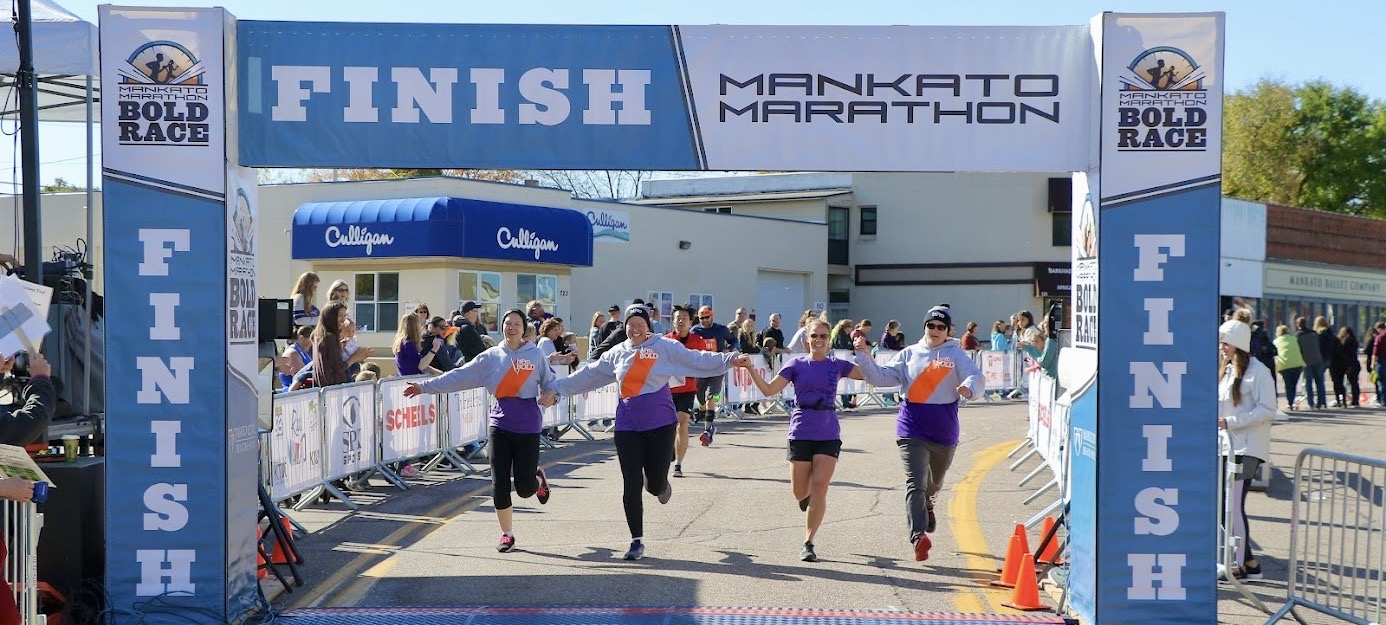 Relay team holding hands crossing the finish