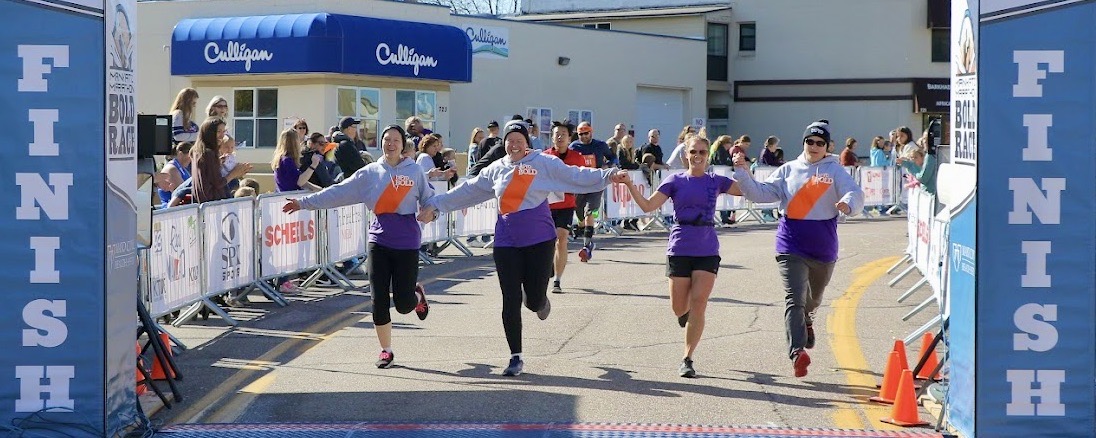 Relay team holding hands crossing the finish